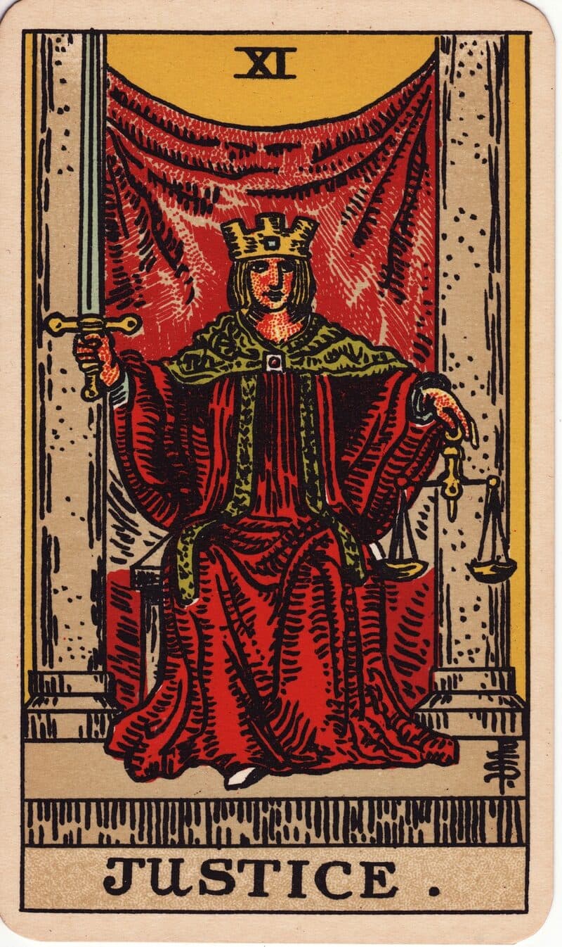 Carta de La Justicia — figura coronada con espada en alto y balanza entre dos pilares, baraja Rider-Waite-Smith